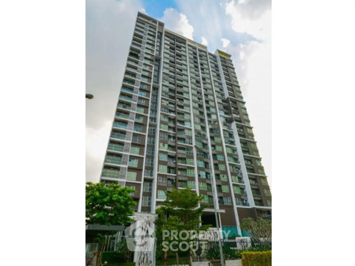 Modern high-rise residential building with lush greenery and clear sky view.