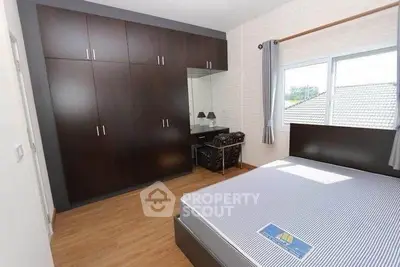 Spacious bedroom with large wardrobe and natural light from window.