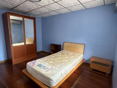 Cozy bedroom with single bed, wooden wardrobe, and nightstand in a serene blue setting.