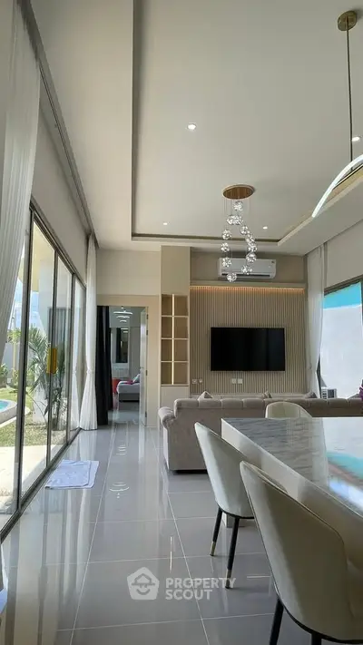 Luxurious modern living room with elegant decor and large windows offering natural light and garden view.