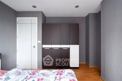 Spacious bedroom with modern wardrobe and floral bedding in a minimalist design.