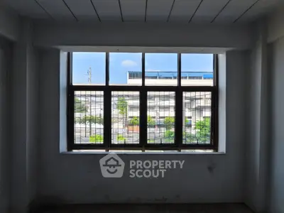 Spacious room with large window offering urban view, perfect for natural light lovers.