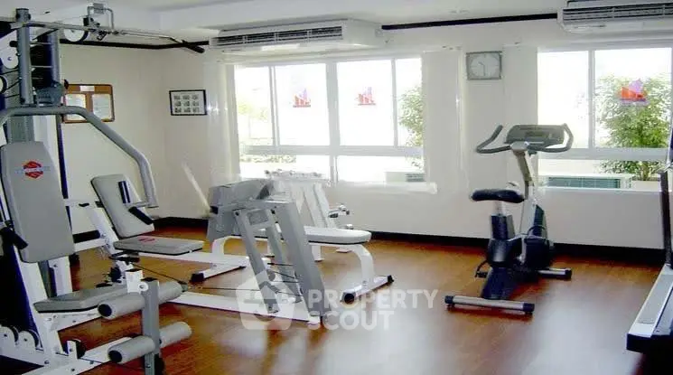 Modern gym with exercise equipment and large windows in a residential building.