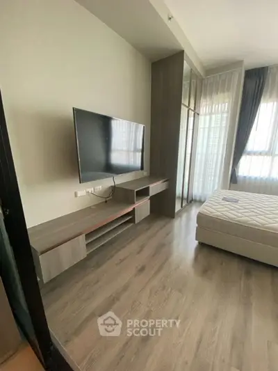 Modern bedroom with sleek TV setup and large window for natural light