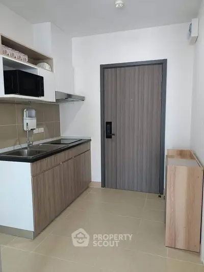 Modern compact kitchen with sleek cabinetry and integrated appliances in a stylish apartment.