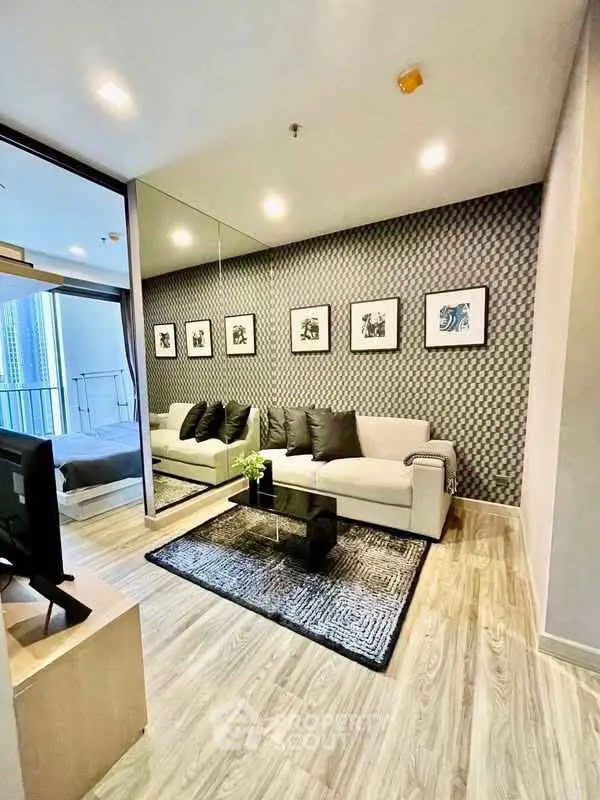 Modern living room with stylish decor and large mirror, featuring a cozy sofa and elegant wall art.