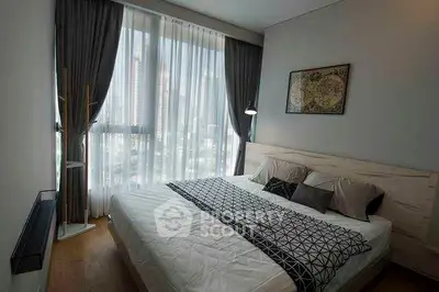 Modern bedroom with large window and stylish decor in urban apartment.