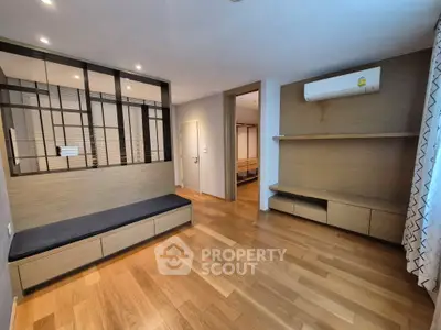 Modern living room with wooden flooring and built-in storage solutions.