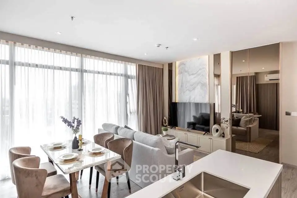 Modern open-plan living room with dining area and large windows in a stylish apartment.