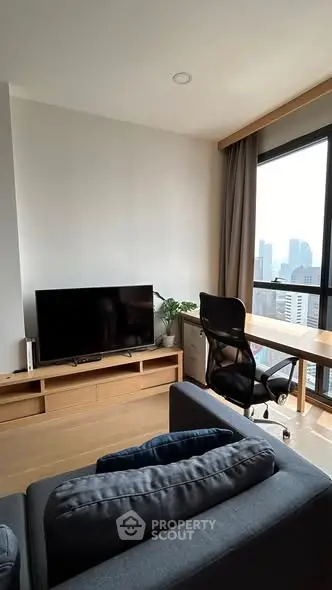 Modern living room with city view, featuring sleek furniture and a large window for natural light.