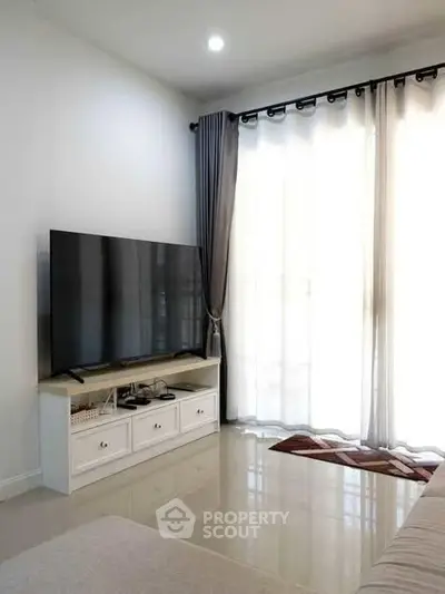 Modern living room with large TV and elegant curtains, perfect for relaxation and entertainment.