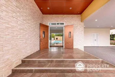 Elegant entrance with stone walls and modern double doors leading to a luxurious pool area.