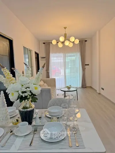 Elegant living room with modern chandelier and stylish dining setup, perfect for entertaining guests.