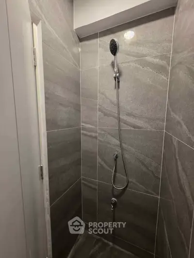 Modern minimalist bathroom shower with sleek gray tiles and rainfall showerhead.