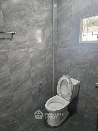 Modern bathroom with sleek gray tiles and a window for natural light.