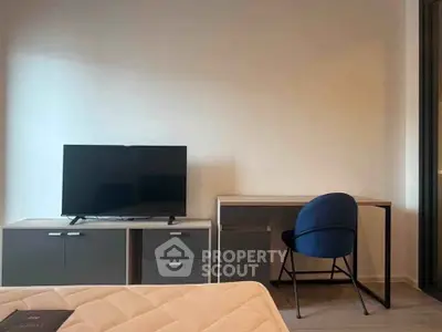 Modern bedroom with TV, desk, and stylish chair, perfect for work and relaxation.