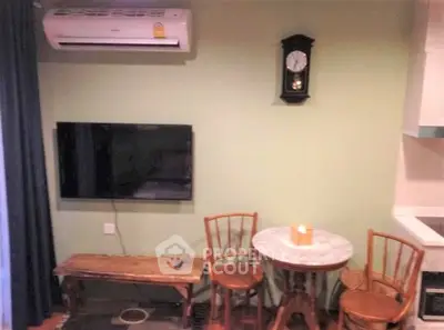 Cozy living area with wall-mounted TV and air conditioner, featuring a small dining set.