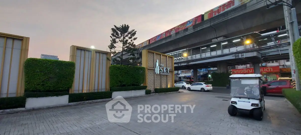 Modern urban entrance with sleek design near elevated train tracks.
