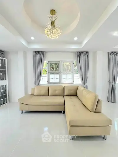 Spacious living room with elegant chandelier and modern beige sectional sofa.