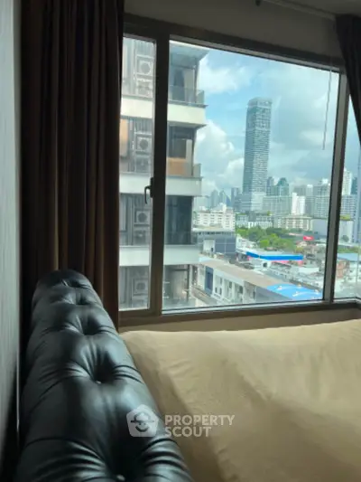 Modern bedroom with city view from large window in high-rise building