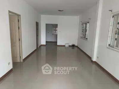 Spacious unfurnished living room with tiled flooring and large windows for natural light.