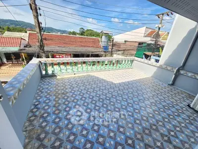 Spacious tiled balcony with scenic view of rooftops and blue sky, perfect for relaxation.