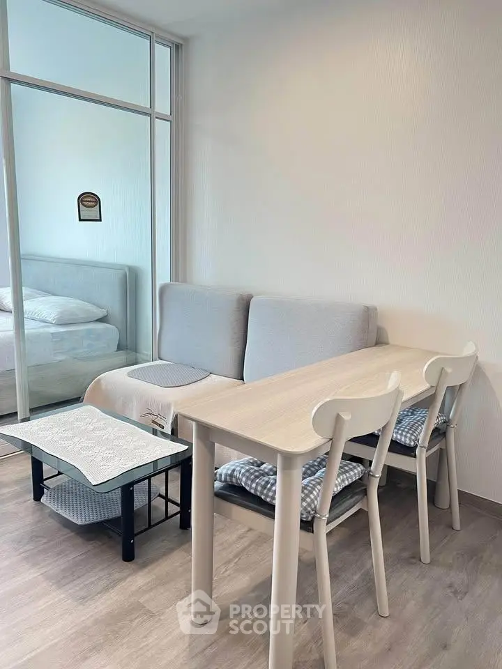 Modern living room with cozy seating and dining area, featuring minimalist design and soft neutral tones.
