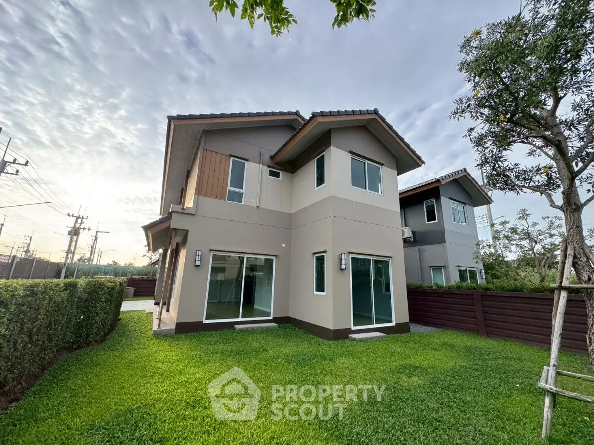 Modern two-story house with lush green lawn and contemporary design.
