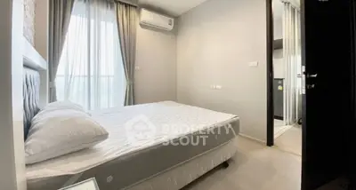Cozy bedroom with large window and air conditioning unit, perfect for relaxation.