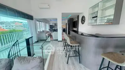 Modern open-plan living room with bar and balcony view in luxury apartment