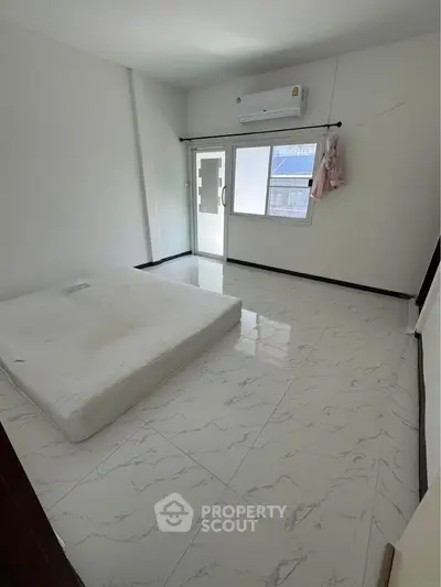 Minimalist bedroom with mattress on tiled floor and air conditioning