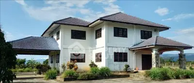 Charming two-story house with tiled roof and lush garden, offering serene mountain views.