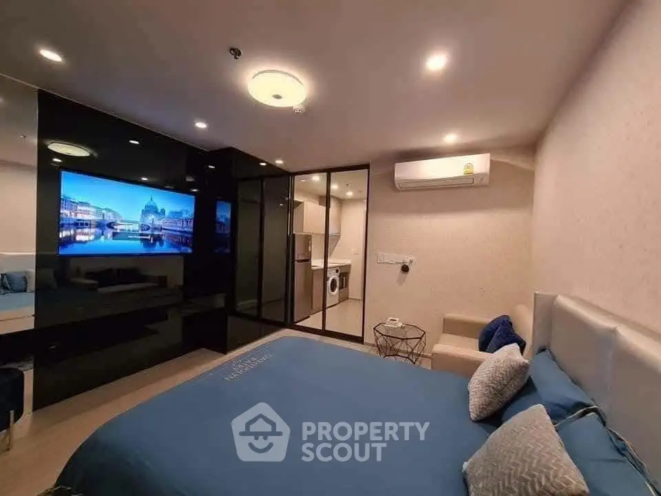 Modern bedroom with sleek design, featuring a large TV, air conditioning, and stylish decor.