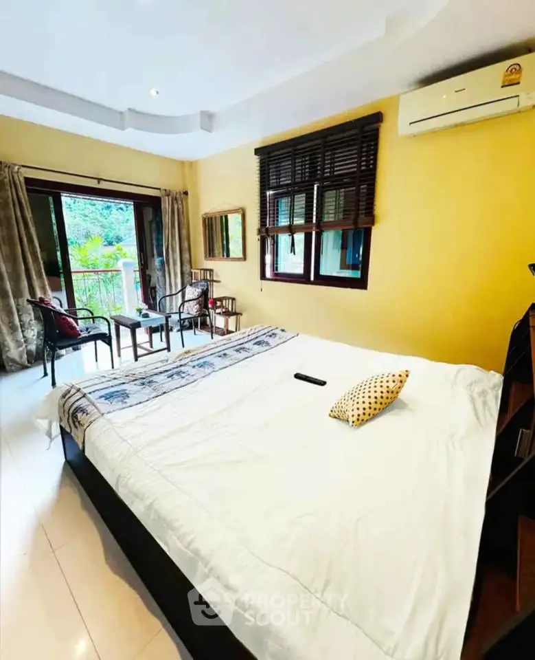 Spacious bedroom with balcony access and natural light, featuring modern decor and air conditioning.