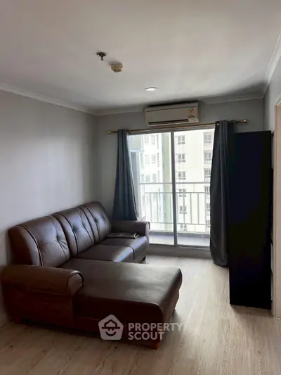 Modern living room with leather sofa and balcony view in a high-rise apartment.