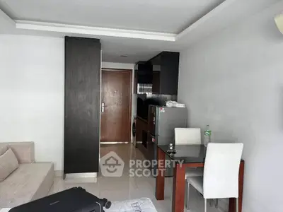 Modern apartment interior with compact kitchen and dining area, featuring sleek furniture and appliances.