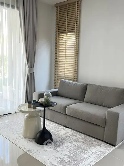Modern living room with sleek gray sofa and stylish coffee table, featuring elegant floor-to-ceiling curtains.