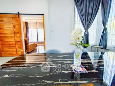 Elegant dining area with marble table and floral centerpiece, adjacent to cozy living room.