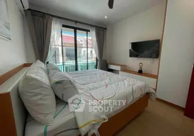 Cozy bedroom with modern decor and natural light, featuring a wall-mounted TV and stylish bedding.