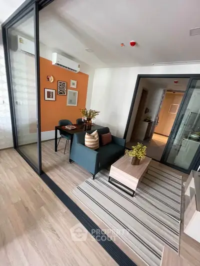 Modern living room with stylish decor and glass partition, featuring cozy seating and vibrant accents.