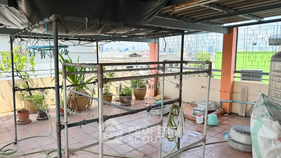 Spacious rooftop terrace with city views and gardening setup, ideal for urban gardening enthusiasts.