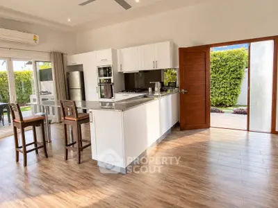 Spacious modern kitchen with open layout and natural light, featuring sleek appliances and wooden flooring.