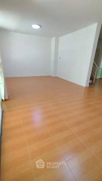 Spacious empty room with wooden flooring and bright natural light