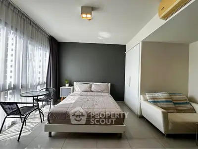 Modern studio apartment with large windows and stylish furnishings in a high-rise building.