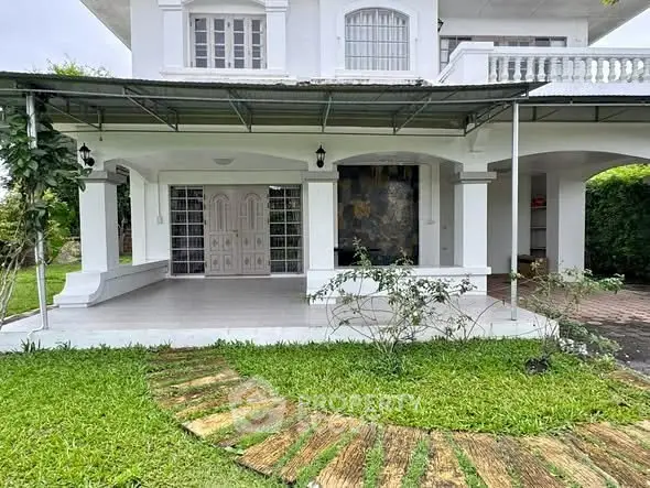 Elegant white two-story house with spacious porch and lush green lawn, perfect for family living.