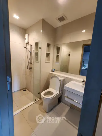 Modern bathroom with glass shower and sleek fixtures in contemporary apartment.