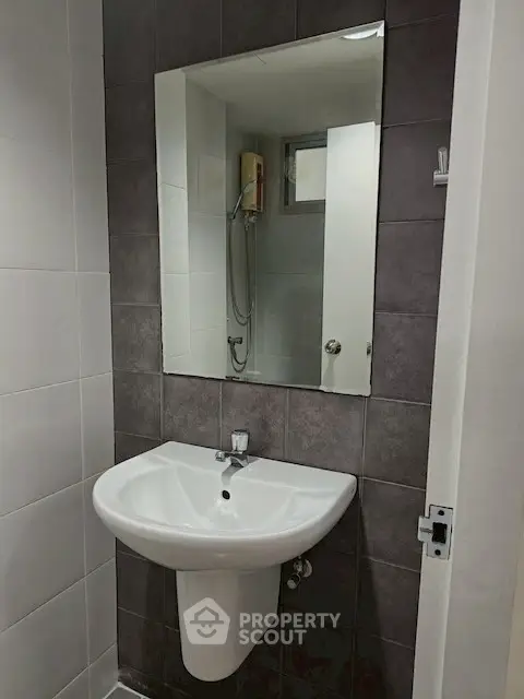 Modern bathroom with sleek sink and mirror, featuring a shower area.