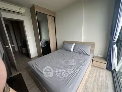 Modern bedroom with sleek wooden furniture and large window for natural light.