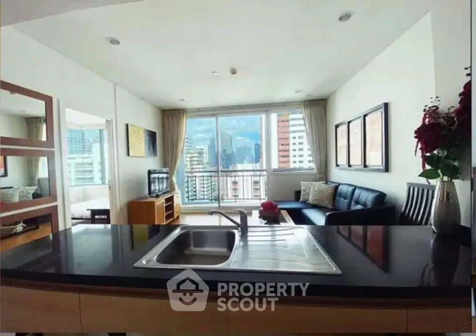 Modern open-layout living room with city view, featuring sleek kitchen island and stylish decor.