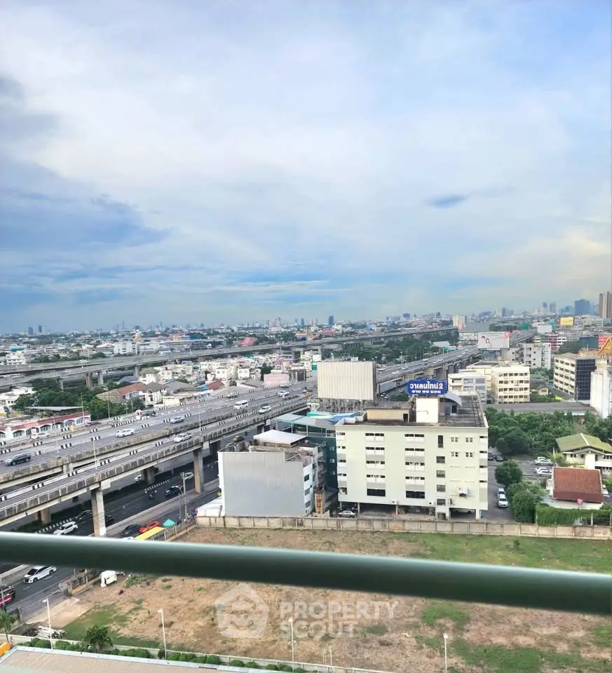 Stunning cityscape view from high-rise balcony overlooking urban skyline and highway.